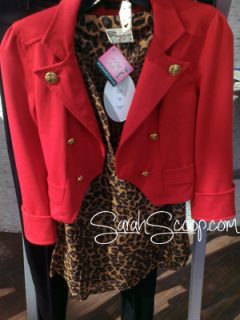A fashionable ensemble ready for the Kansas City Fashion Week Kickoff Party, consisting of a red jacket and leopard print top on a hanger.