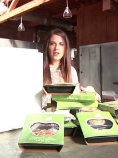A woman in front of a kitchen with Diet to Go boxes of food.