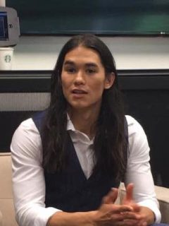 A long-haired man sitting in a chair during a Descendants 2 interview, featuring Booboo Stewart.