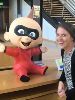 A woman standing next to an official Disney Pixar statue of the Incredibles.