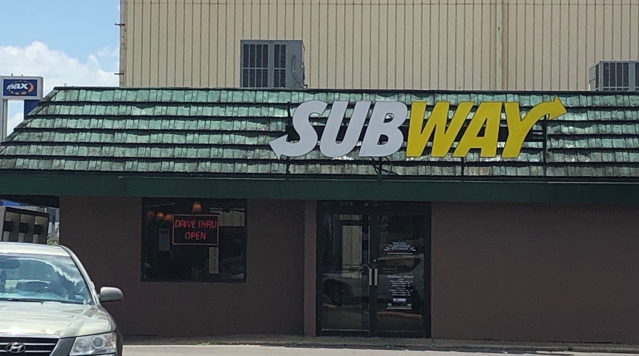 A car is parked in front of a Subway restaurant.