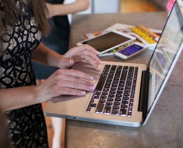 A woman typing on a laptop at a bar while enjoying free Wi-Fi.