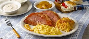 A Low Calorie Guide to a breakfast plate with ham, eggs, and biscuits on a table.