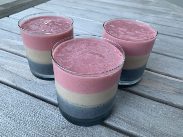Three colorful smoothies on a wooden table.