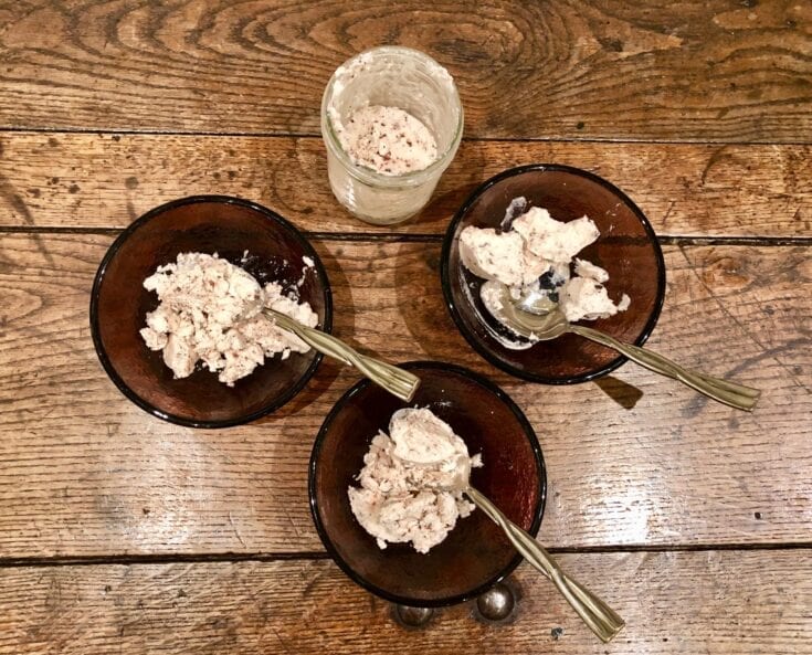 Three bowls of ice cream on a wooden table.