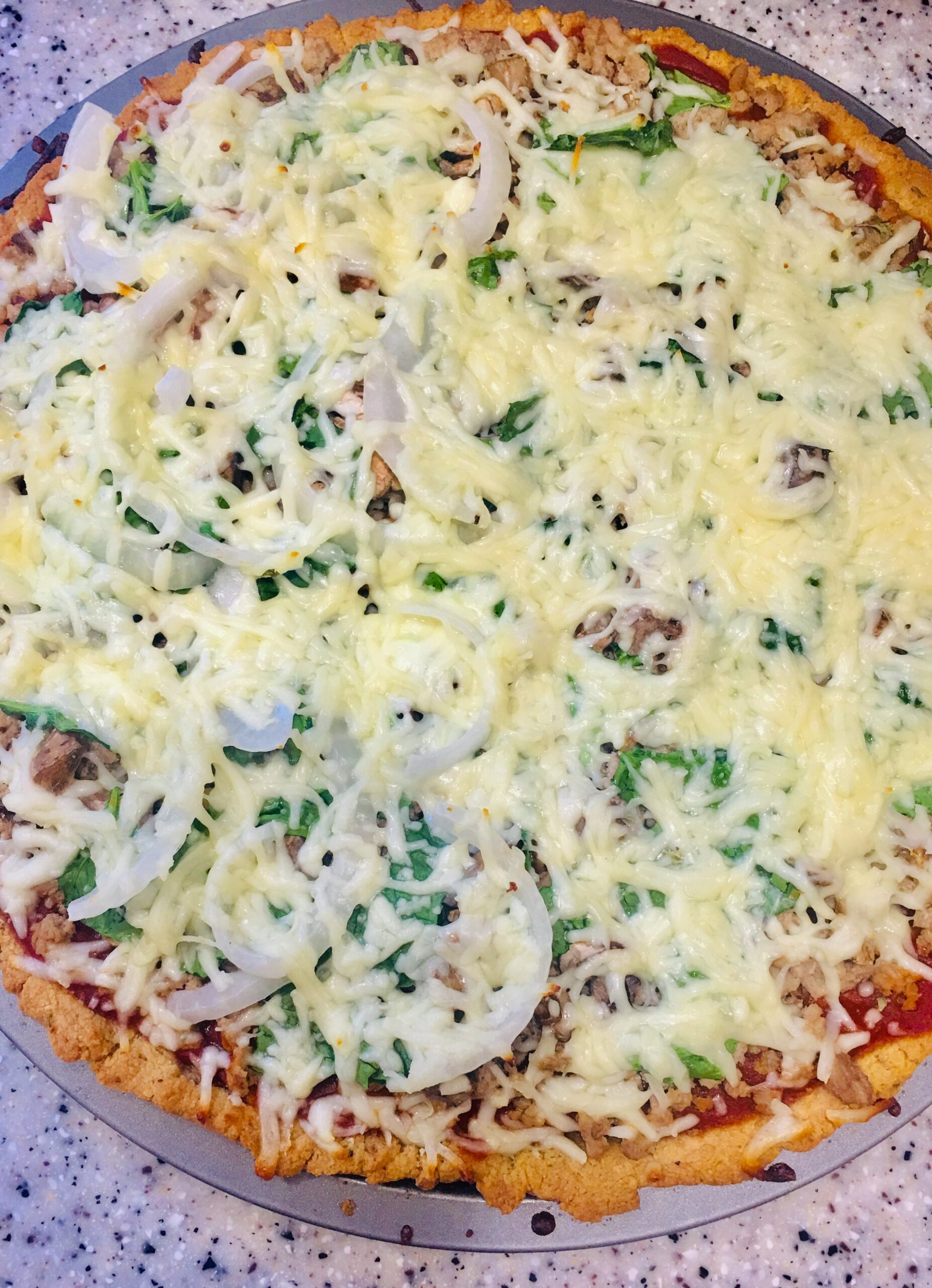 A Keto-Friendly Ground Turkey Pizza is sitting on a pan on a counter.