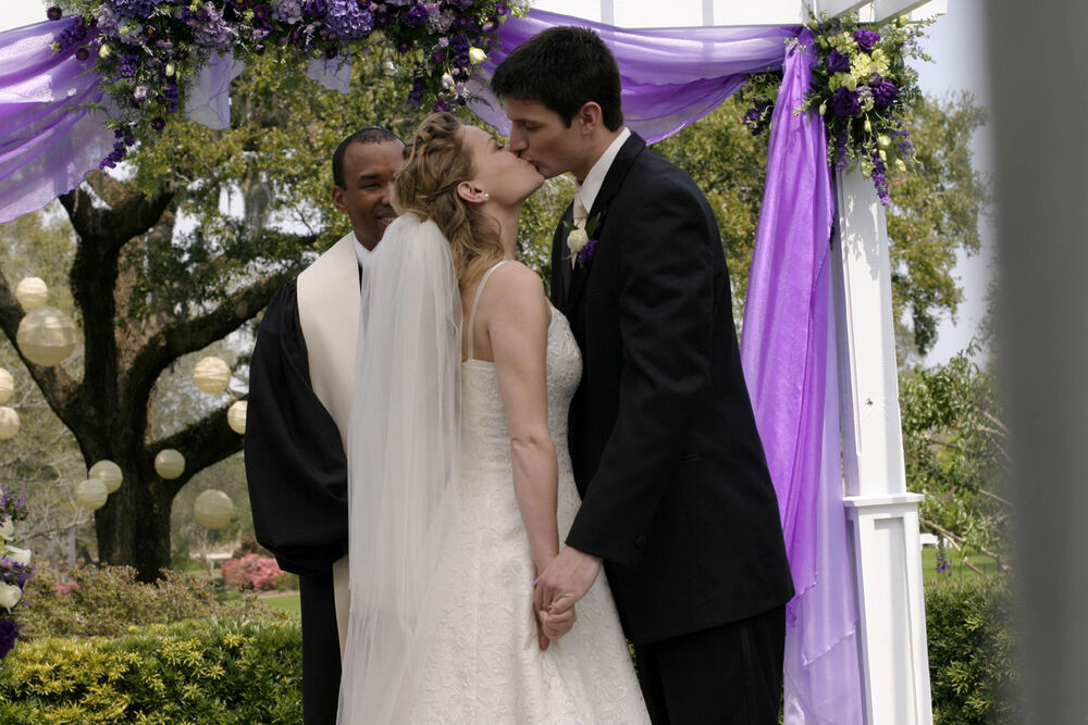 A Naley couple kisses under a purple wedding arch.