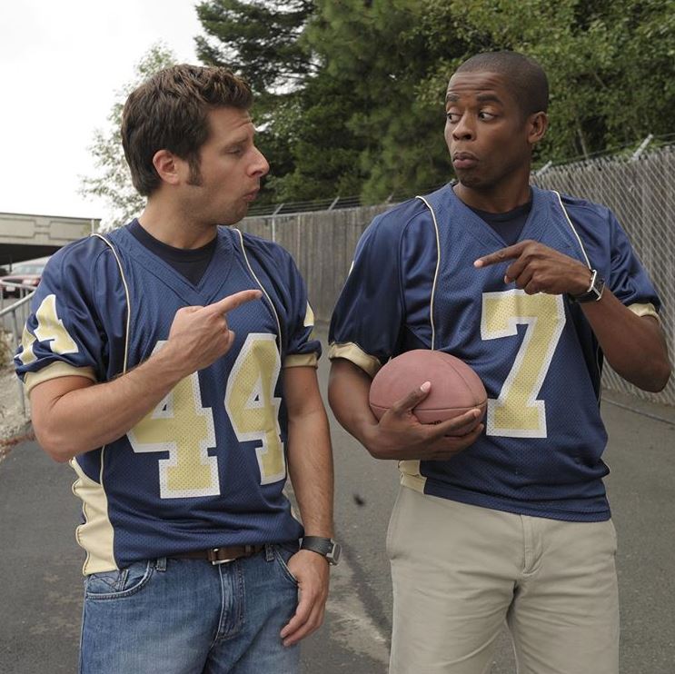 Two men in football uniforms standing next to each other in Psych 2: Lassie Come Home.