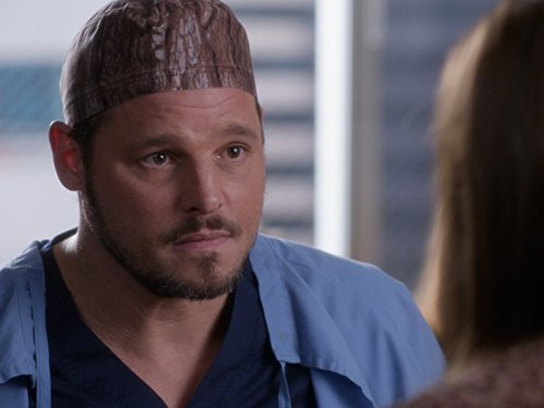 A man in Grey's scrubs is looking at a woman.
