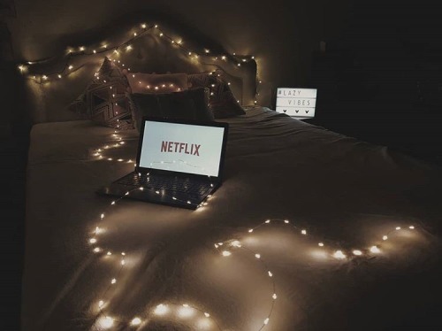 A bed with lights and a laptop showcasing shows from the early 2000s.