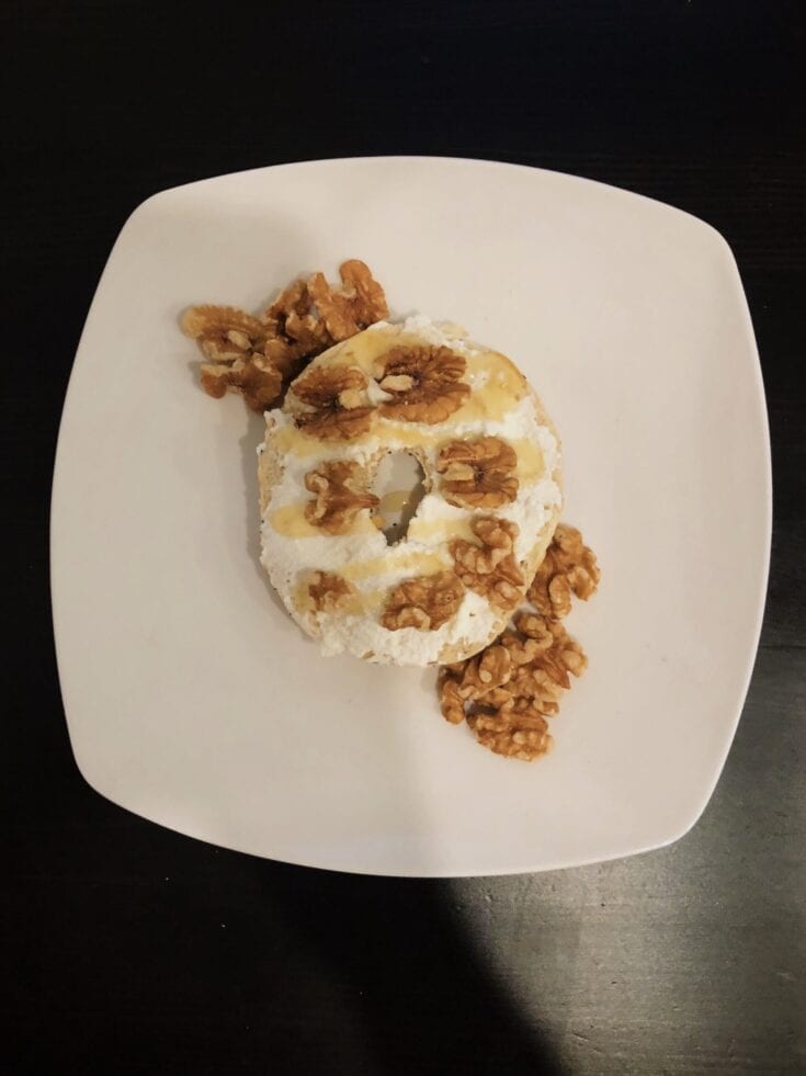 A plate with a donut and walnuts.