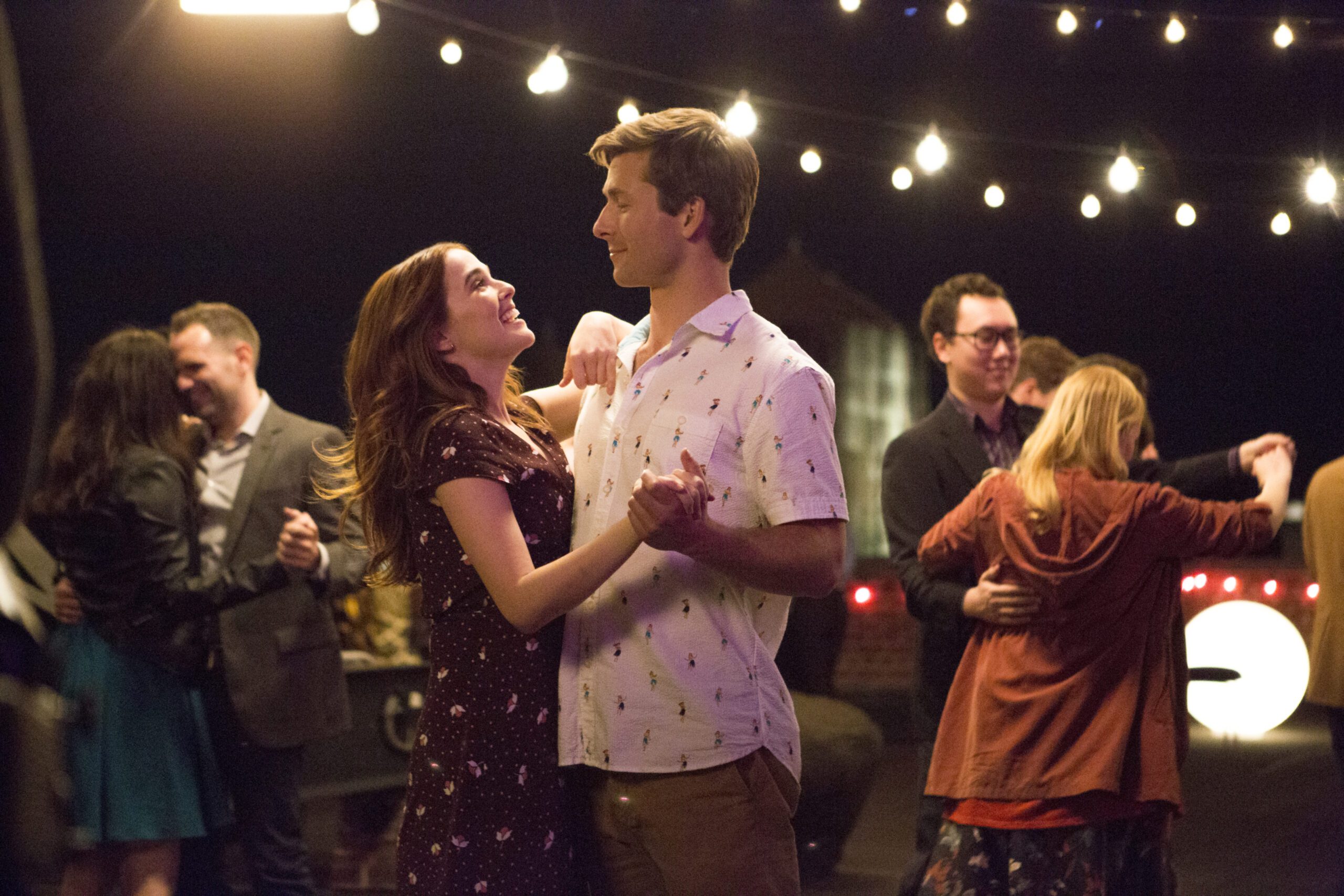 A man and woman dancing at a lively party unfolding in a heartwarming Netflix romantic comedy.