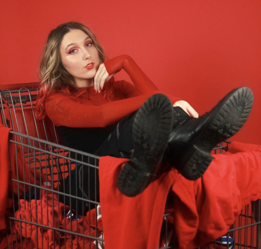 Michelle sitting in a shopping cart on a red background.