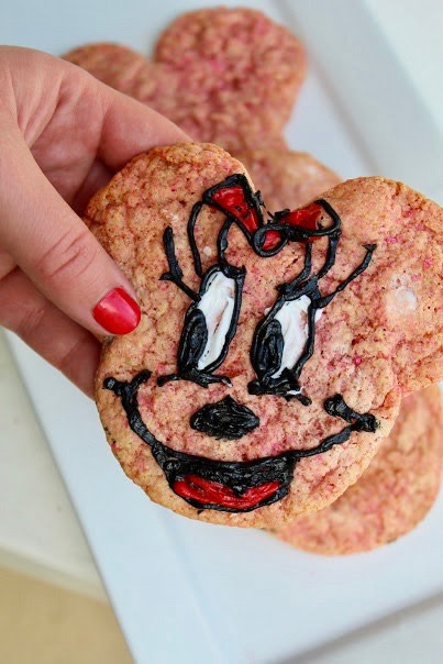 A person is holding up a Minnie Mouse shaped cookie from the Minnie Mouse cookie jar.