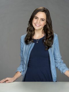 A young woman, one of the best Hallmark movie actresses, posing in front of a gray background.