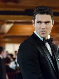 Ryan Paevey dressed in a tuxedo, standing in a room.