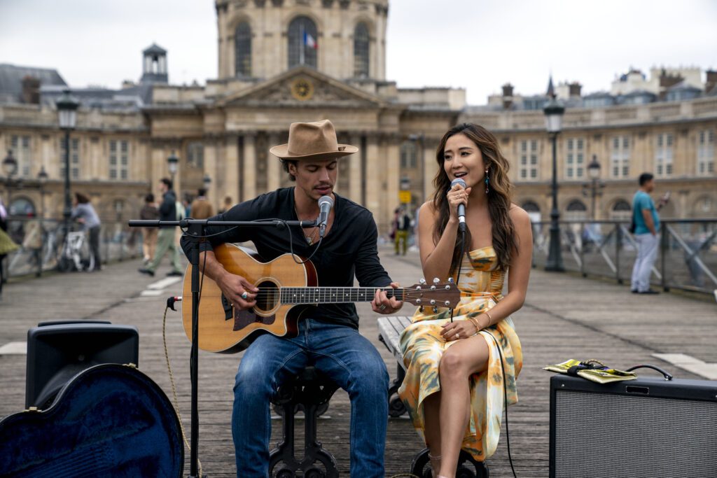 (L to R) Kevin Dias as Benoit, Ashley Park as Mindy in episode 206 of Emily in Paris. 