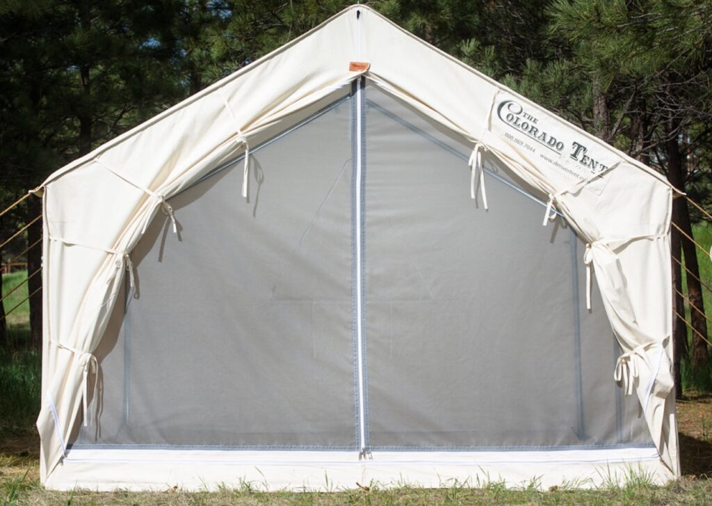 The Colorado Canvas Wall Tent is pictured. This tent is white with a 3-way vertical zipper door. 