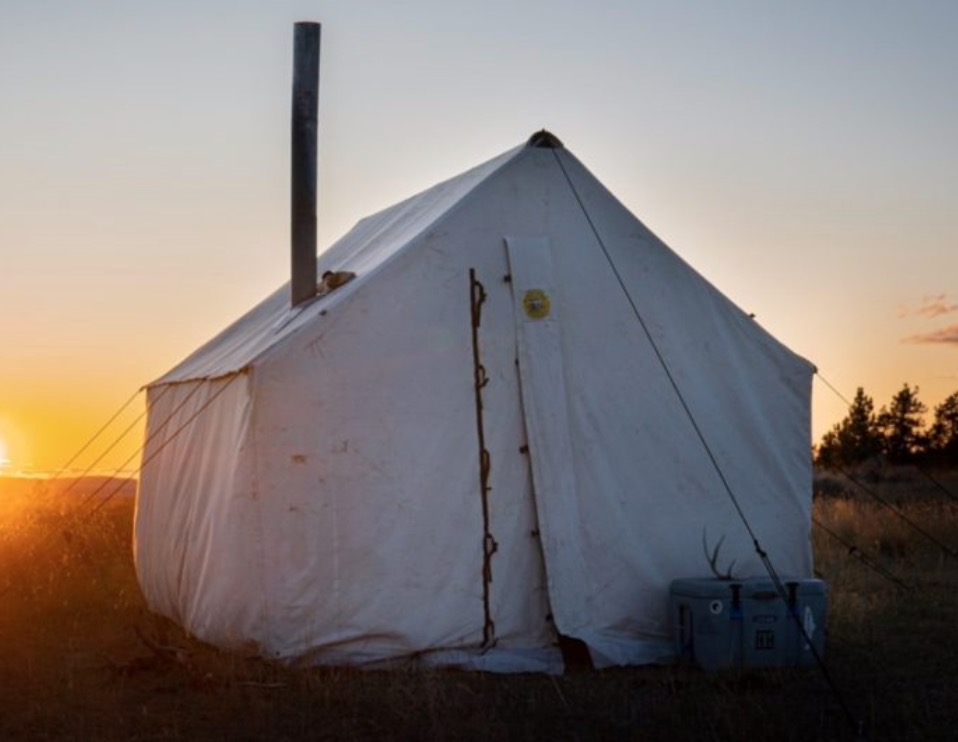 The Traditional Montana Canvas Tent is pictured. The tent is smaller than the last two, but with the same size and color (triangular top, square bottom, white color). 