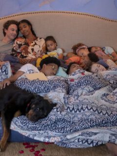 A group of people and a dog on a bed.