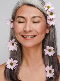 A woman with gray hair and flowers in her hair, exploring laser hair removal for gray hair.