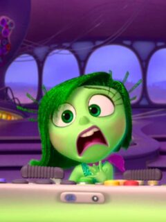 A cartoon character with green hair is sitting at a table, embodying sadness.