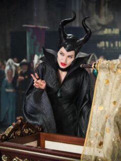 Maleficent with a cradle, quoting fools in front of a crowd.