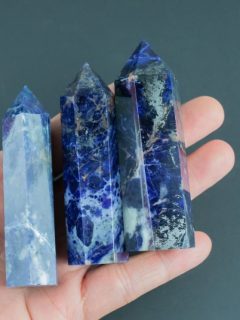 Three lapis lazuli points, powerful crystals for cleansing, held in a person's hand to enhance their aura.