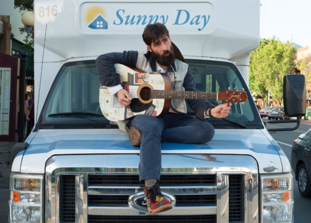 Devon playing guitar while sitting on a van in wine country