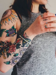A woman with meaningful tattoos holding a cup of coffee.