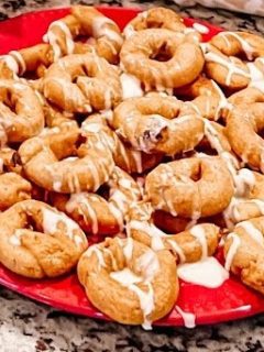 Baked pumpkin donuts on a red plate with icing on them.