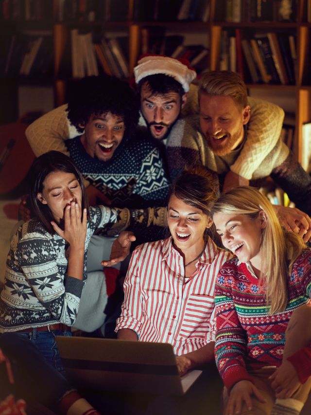 family in christmas sweaters looking at computer
