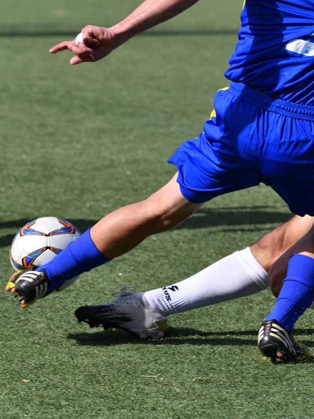 man in blue kicking soccer ball