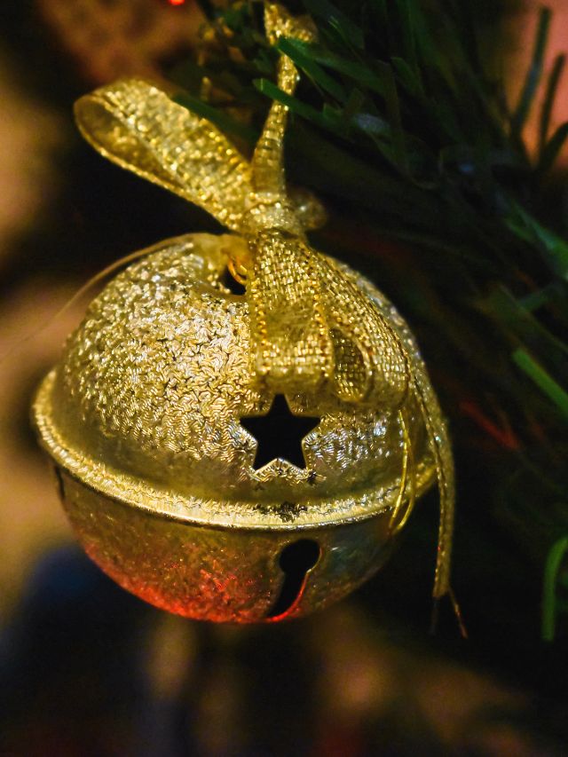 gold jingle bell hanging on a christmas tree