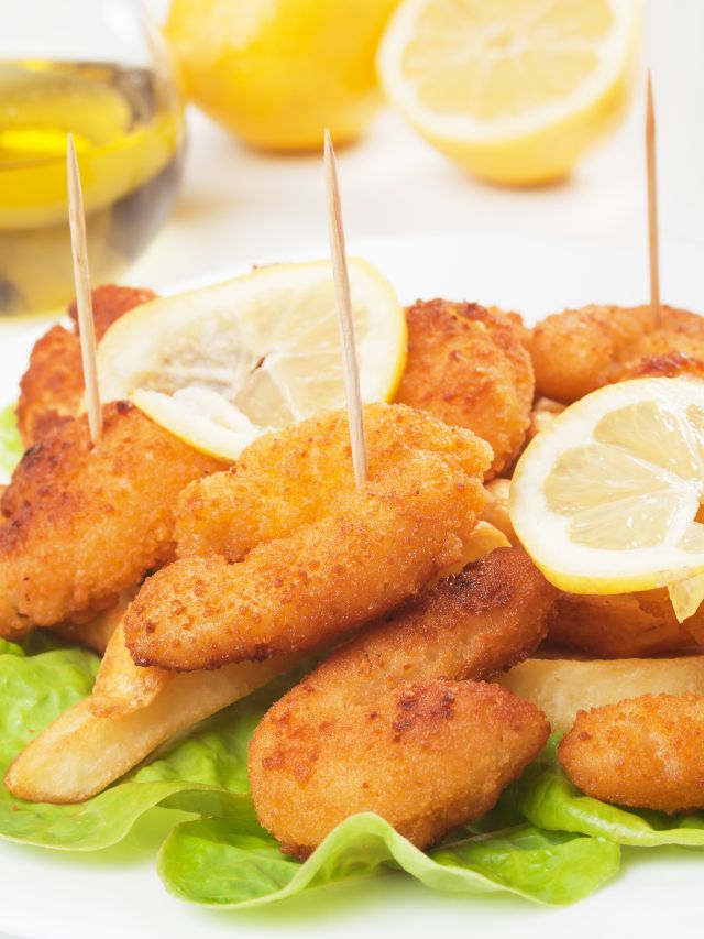 breaded shrimp with lemon and toothpicks on bed of greens