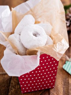 Best foodie gift for Christmas - powdered sugar donuts in a box on a wooden table.