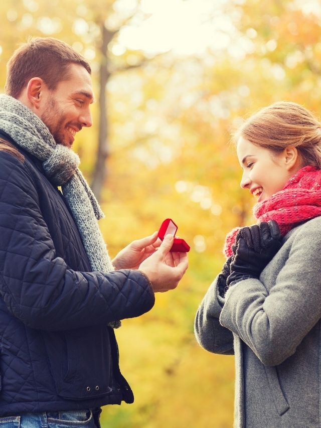 smiling couple with engagement ring in small red gift box