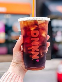A person enjoying a cup of iced coffee from Dunkin Donuts, one of their new and festive Christmas drinks.
