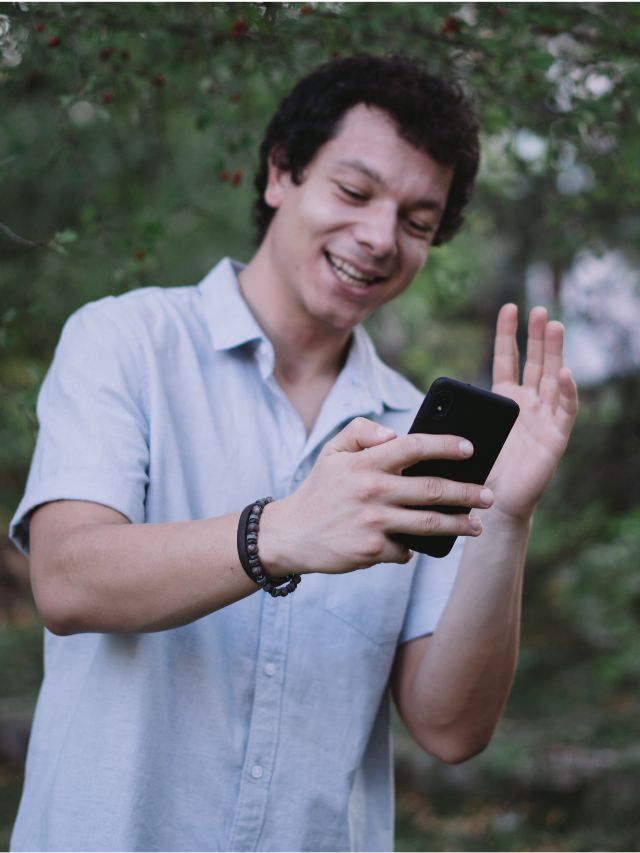 man smiling and waving to his phone