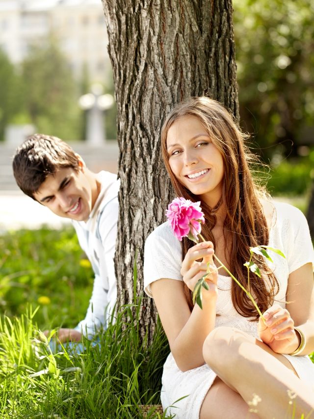 couple sitting around a tree, the woman has a flower