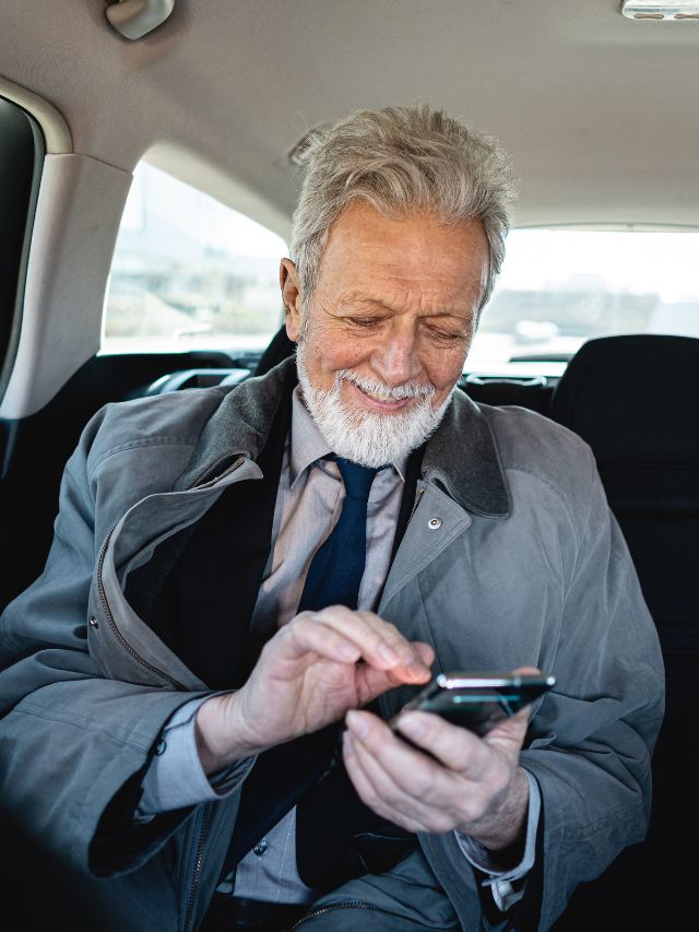 man smiling at phone while sitting in car