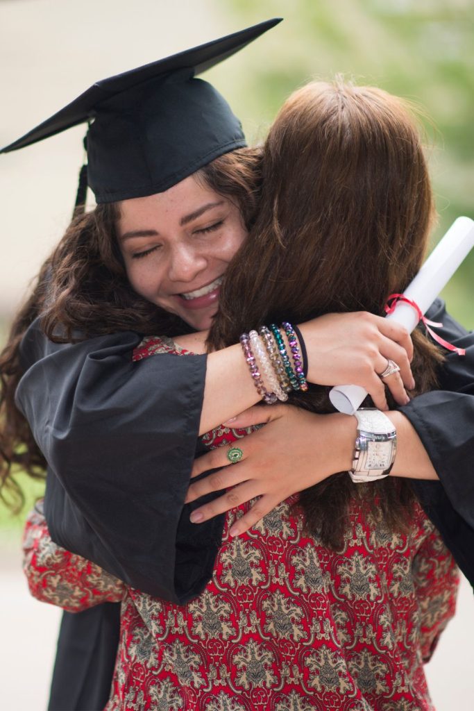 a college graduate hugging a family member