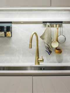 A white kitchen with a gold faucet.