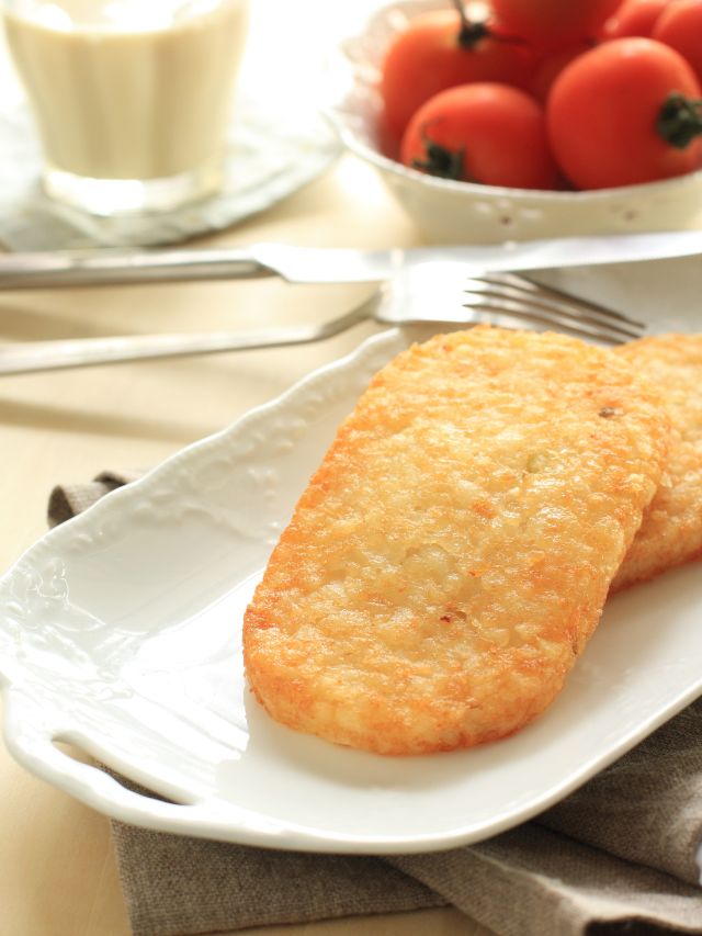 hash browns  on plate with tomatoes in background
