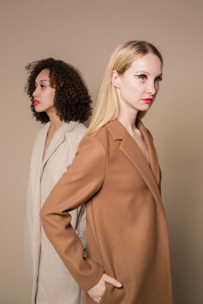 two women posing in long coats