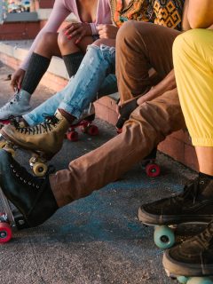 A group of people sitting on skateboards, rollerblading vs roller skating.