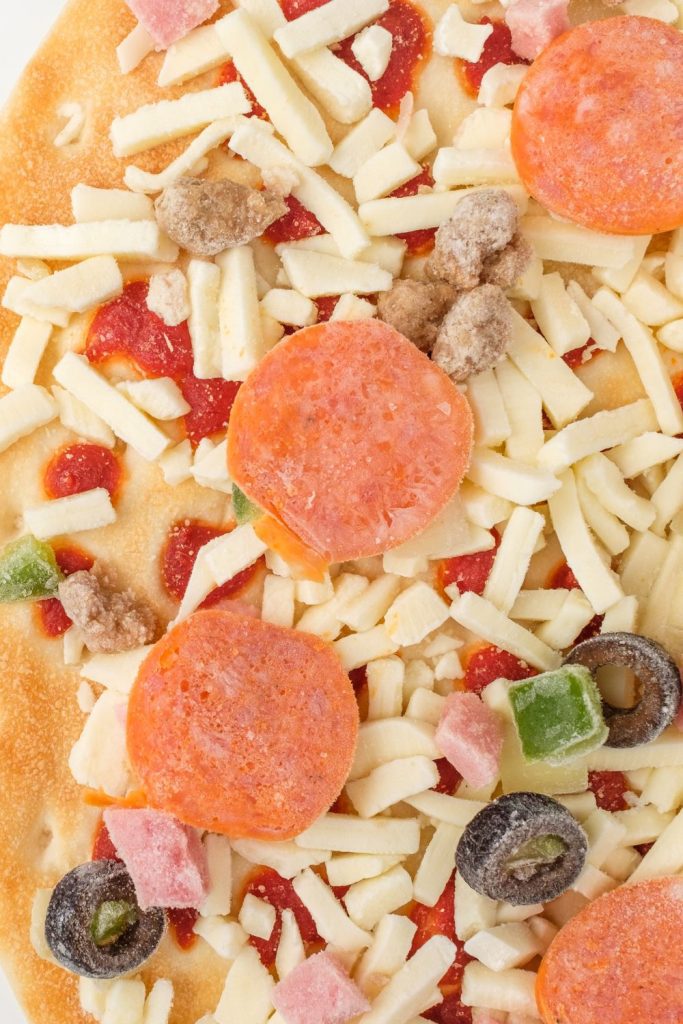 frozen pizza with olives, pepperoni, cheese, ham, and peppers