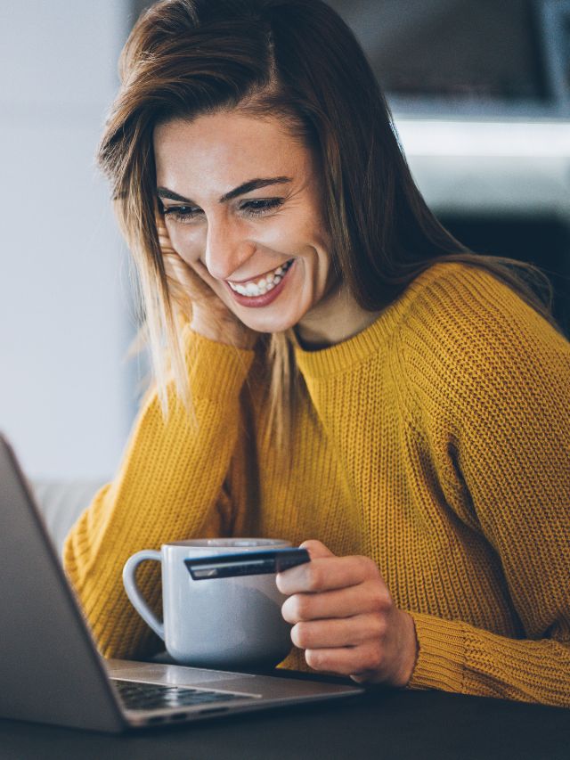 woman with coffee smiling at her computer