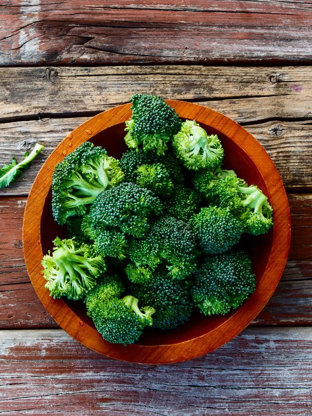 fresh green broccoli in wood bowl over rustic wood background