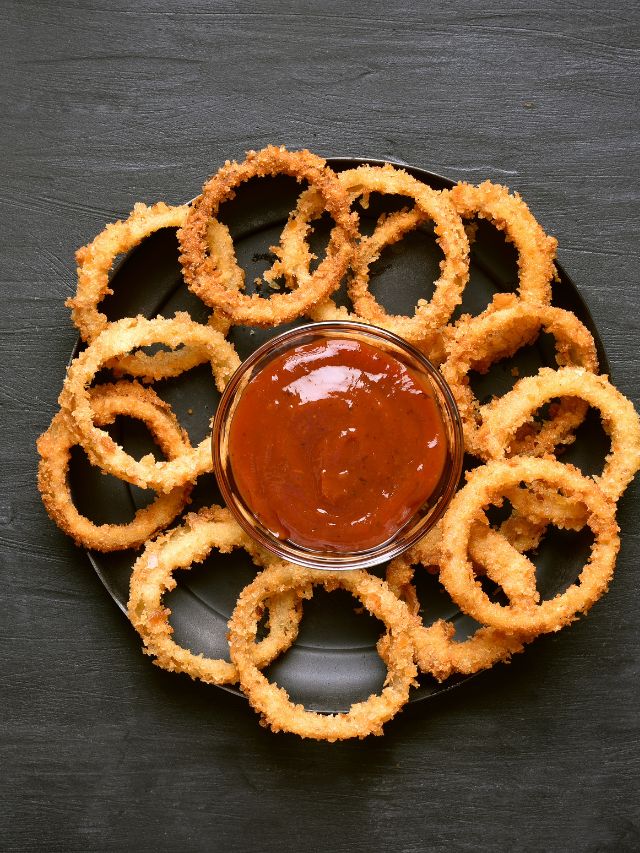 crunchy fried onion rings on dark background with copy sauce